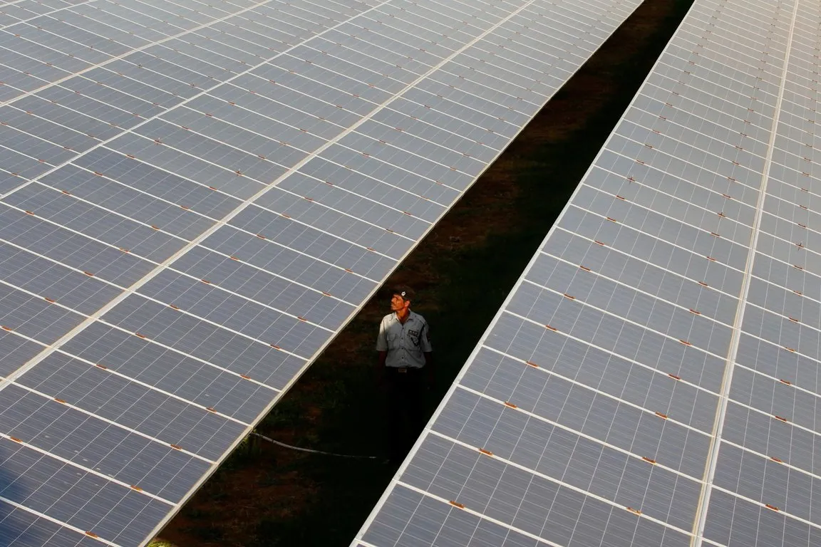 Aerial view of a large solar plant with an engineer walking between rows