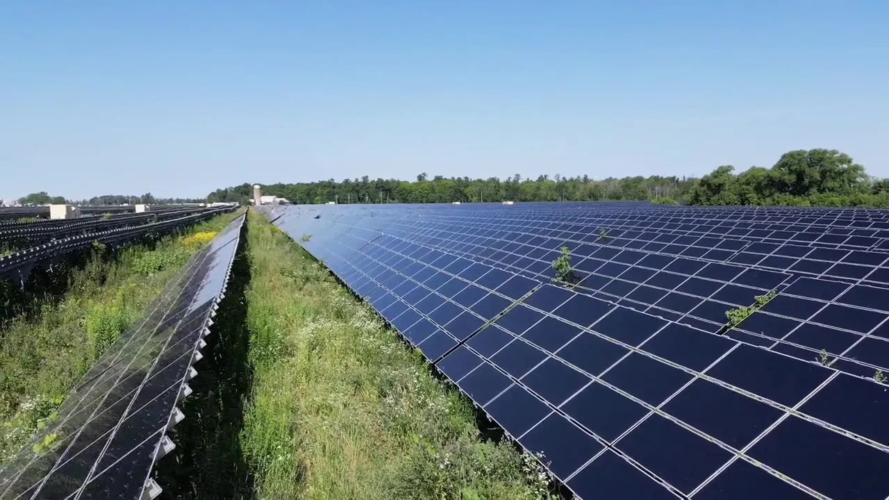 Drone view flying low over a large ground-mounted solar farm